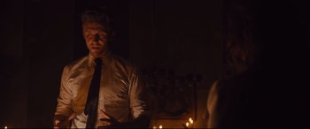 Movie still from “High-Rise” (2015), directed by Ben Wheatley – A man standing in front of candles in a dark room; Medium shot, Over the shoulder angle