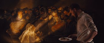 Movie still from “High-Rise” (2015), directed by Ben Wheatley – A group of people gathered around a plate of food; Medium shot, Over the shoulder angle