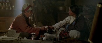 Movie still from “Himalaya” (1999), directed by Eric Valli – A man and a woman sitting at a table; Medium shot, High angle