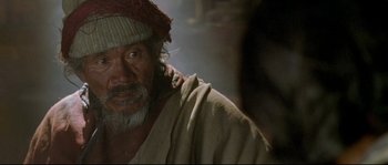 Movie still from “Himalaya” (1999), directed by Eric Valli – An old man with a beard wearing a red hat; Close Up shot, Over the shoulder angle