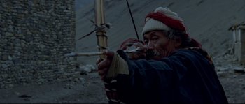 Movie still from “Himalaya” (1999), directed by Eric Valli – An older man is holding a bow and arrow; Medium shot, Low angle