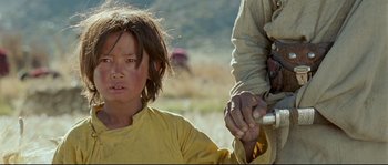 Movie still from “Himalaya” (1999), directed by Eric Valli – A young boy is holding a man's hand; Close Up shot, Low angle