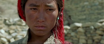 Movie still from “Himalaya” (1999), directed by Eric Valli – A person with a red string in their hair; Close Up shot, High angle