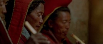 Movie still from “Himalaya” (1999), directed by Eric Valli – Two people are sitting in a room holding a stick; Extreme Close Up shot, High angle