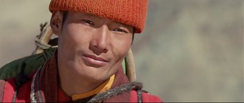 Movie still from “Himalaya” (1999), directed by Eric Valli – A man wearing a red hat and a yellow jacket; Close Up shot, High angle