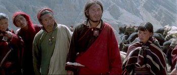 Movie still from “Himalaya” (1999), directed by Eric Valli – A man in a red and black jacket is standing next to a man in a red and black jacket; Medium shot, High angle