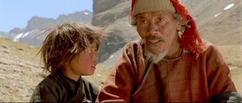 Movie still from “Himalaya” (1999), directed by Eric Valli – An older man and a young boy are sitting in a field; Close Up shot, Low angle