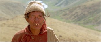 Movie still from “Himalaya” (1999), directed by Eric Valli – A man with a hat on and a beard; Close Up shot, High angle