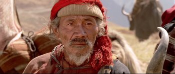 Movie still from “Himalaya” (1999), directed by Eric Valli – An old man with a beard wearing a red hat; Close Up shot, High angle