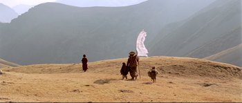 Movie still from “Himalaya” (1999), directed by Eric Valli – A group of people standing on top of a hill; Extreme Wide shot, Low angle