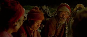 Movie still from “Himalaya” (1999), directed by Eric Valli – A group of men sitting next to each other; Medium shot, High angle
