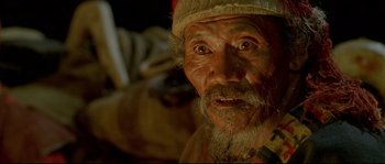 Movie still from “Himalaya” (1999), directed by Eric Valli – An old man with a beard wearing a hat; Close Up shot, High angle