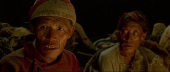 Movie still from “Himalaya” (1999), directed by Eric Valli – An old man with a hat on and a lot of other people in the background; Close Up shot, High angle