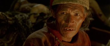Movie still from “Himalaya” (1999), directed by Eric Valli – An older man with a hat on looking into the camera; Extreme Close Up shot, High angle