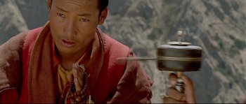 Movie still from “Himalaya” (1999), directed by Eric Valli – A man in a red shirt holding a metal container; Close Up shot, High angle