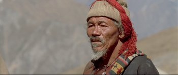 Movie still from “Himalaya” (1999), directed by Eric Valli – An old man with a beard wearing a hat; Close Up shot, High angle