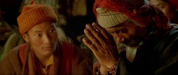 Movie still from “Himalaya” (1999), directed by Eric Valli – An old man praying with his hands in front of a woman; Close Up shot, High angle