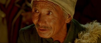 Movie still from “Himalaya” (1999), directed by Eric Valli – An old man with a mustache wearing a hat; Extreme Close Up shot, High angle
