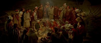Movie still from “Himalaya” (1999), directed by Eric Valli – A group of people gathered around a pile of clothes; Wide shot, High angle