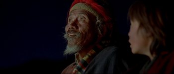 Movie still from “Himalaya” (1999), directed by Eric Valli – An old man with a beard and a red hat; Close Up shot, Low angle