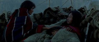 Movie still from “Himalaya” (1999), directed by Eric Valli – Two people sitting on a pile of rocks; Medium shot, High angle
