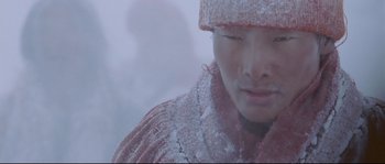 Movie still from “Himalaya” (1999), directed by Eric Valli – A man in a red jacket and a hat in the snow; Close Up shot, Low angle