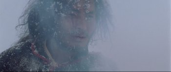 Movie still from “Himalaya” (1999), directed by Eric Valli – A man with long hair and a beard is standing in the fog; Close Up shot, Low angle