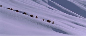 Movie still from “Himalaya” (1999), directed by Eric Valli – A group of people walking up a snow covered slope; Extreme Wide shot, High angle