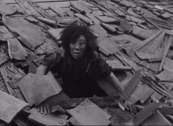 Movie still from “Hiroshima Mon Amour” (1959), directed by Alain Resnais – A black and white photo of a woman in a pile of rubble; Medium shot, Overhead angle