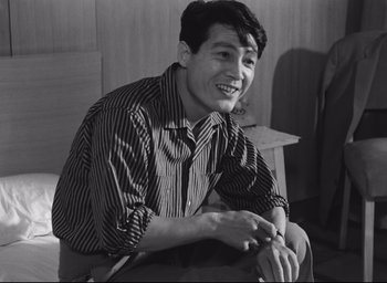 Movie still from “Hiroshima Mon Amour” (1959), directed by Alain Resnais – Black and white photograph of a young man smiling; Close Up shot, Low angle