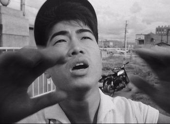 Movie still from “Hiroshima Mon Amour” (1959), directed by Alain Resnais – A black - and - white photo of a man in a baseball cap; Close Up shot, Low angle