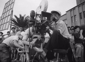 Movie still from “Hiroshima Mon Amour” (1959), directed by Alain Resnais – An old black and white photo of a man sitting in a chair; Extreme Close Up shot, Low angle