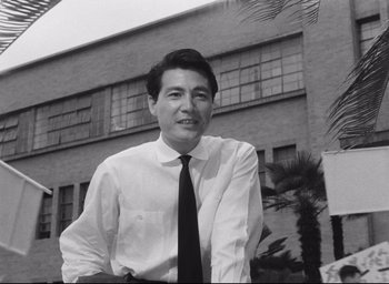 Movie still from “Hiroshima Mon Amour” (1959), directed by Alain Resnais – Black and white photograph of a man wearing a shirt and tie; Medium shot, Low angle