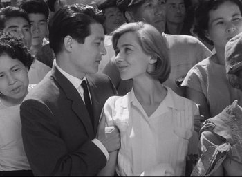 Movie still from “Hiroshima Mon Amour” (1959), directed by Alain Resnais – A man and a woman standing next to each other in a crowd; Medium shot, Low angle
