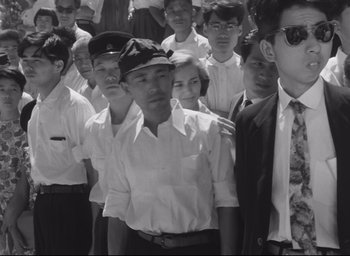 Movie still from “Hiroshima Mon Amour” (1959), directed by Alain Resnais – Black and white photograph of a group of people in uniform; Medium shot, High angle