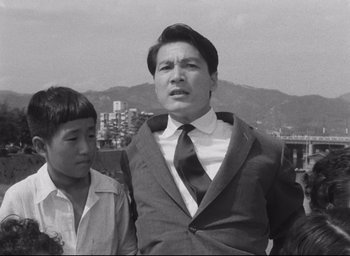 Movie still from “Hiroshima Mon Amour” (1959), directed by Alain Resnais – A black and white photo of a man and a boy; Medium shot, Low angle