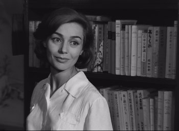 Movie still from “Hiroshima Mon Amour” (1959), directed by Alain Resnais – A black and white photo of a woman in front of a book shelf; Close Up shot, Low angle