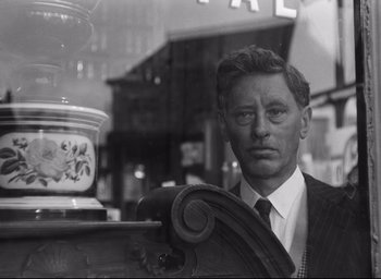 Movie still from “Hiroshima Mon Amour” (1959), directed by Alain Resnais – A black and white photo of a man standing in front of a table; Close Up shot, Low angle