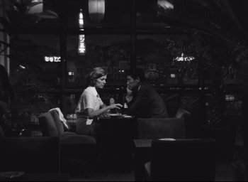 Movie still from “Hiroshima Mon Amour” (1959), directed by Alain Resnais – A man and a woman sitting at a table in front of each other; Medium shot, Low angle