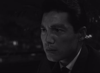 Movie still from “Hiroshima Mon Amour” (1959), directed by Alain Resnais – Black and white photograph of a man in a suit; Close Up shot, High angle