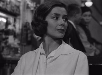 Movie still from “Hiroshima Mon Amour” (1959), directed by Alain Resnais – An old black and white photo of a woman in a lab coat; Close Up shot, Over the shoulder angle