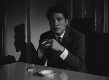 Movie still from “Hiroshima Mon Amour” (1959), directed by Alain Resnais – A black and white photo of a man smoking a cigarette; Close Up shot, Low angle