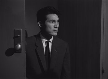 Movie still from “Hiroshima Mon Amour” (1959), directed by Alain Resnais – Black and white photograph of a man in a suit; Close Up shot, Low angle