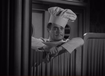 Movie still from “History Is Made at Night” (1937), directed by Frank Borzage – A man wearing a chef's hat is leaning on a rail; Medium shot, High angle
