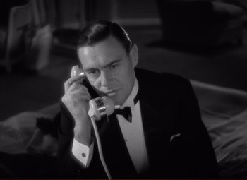Movie still from “History Is Made at Night” (1937), directed by Frank Borzage – A black and white photo of a man talking on a phone; Close Up shot, High angle