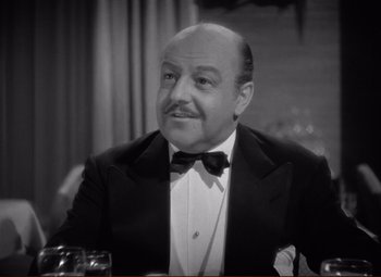 Movie still from “History Is Made at Night” (1937), directed by Frank Borzage – An older man wearing a suit and bow tie sitting at a table; Close Up shot, High angle