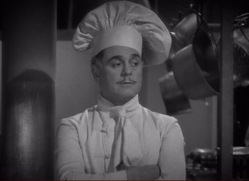 Movie still from “History Is Made at Night” (1937), directed by Frank Borzage – A black and white photo of a man wearing a chef's hat; Medium shot, Low angle