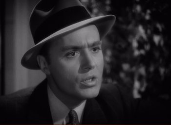 Movie still from “History Is Made at Night” (1937), directed by Frank Borzage – A man wearing a hat and a suit and tie; Close Up shot, High angle