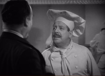 Movie still from “History Is Made at Night” (1937), directed by Frank Borzage – A black - and - white photo of a man wearing a chef's hat; Medium shot, Over the shoulder angle
