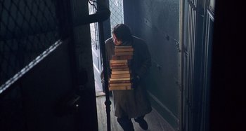 Movie still from “Unfaithful” (2002), directed by Adrian Lyne – A woman holding a stack of books in a doorway; Wide shot, Overhead angle